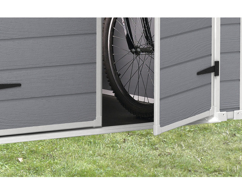 Detailansicht einer geöffneten Tür eines Gerätehauses mit Fahrrad im Inneren