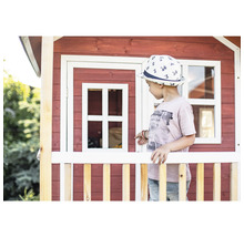 Kind vor einem Spielhaus aus Holz mit Fenster und Zaun