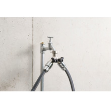 Wasserhahn mit zwei Anschlüssen und Schlauchanschlüssen vor einer Betonwand