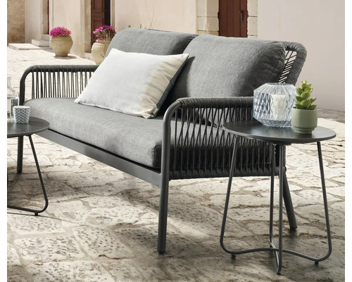 Graues Gartensofa mit zwei Sitzen und zwei grauen Kissen auf einer Terrasse mit zwei Beistelltischen.