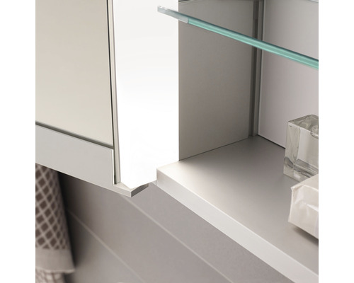 Detailaufnahme eines Badezimmerspiegelschranks mit Glasablage und Handtuch