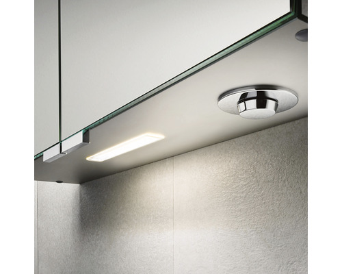 Detailansicht eines Spiegelschranks mit integrierter Beleuchtung und einem runden Schalter