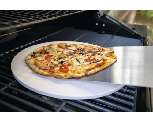 Pizza auf Pizzastein mit Pizzaschieber im Grill