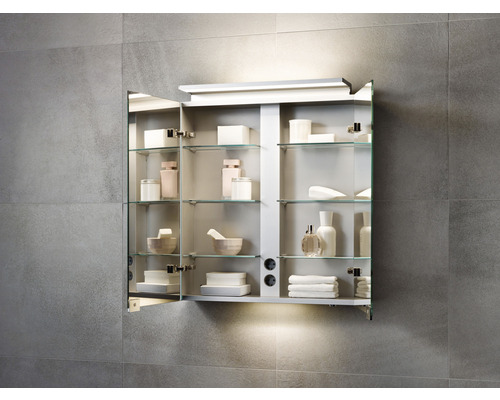 Offener Spiegelschrank mit Glasablagen und Badartikeln an einer gefliesten Wand