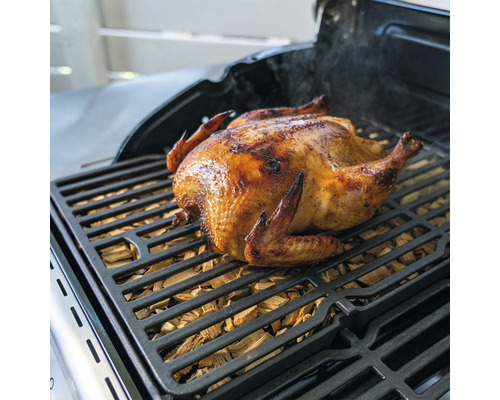 Gegrilltes Hähnchen auf einem Grillrost mit Räucherholz