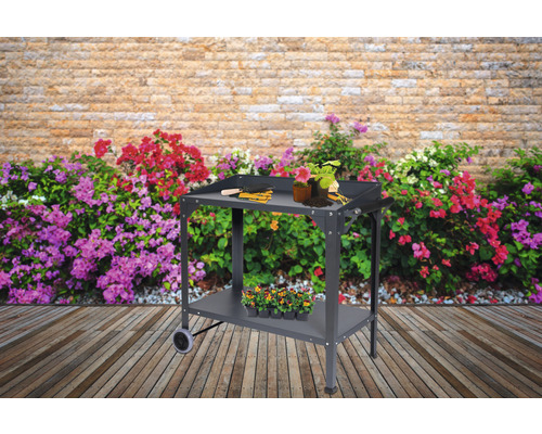 Rollbarer Gartentisch mit Ablage und Gartenzubehör vor Blumenwand
