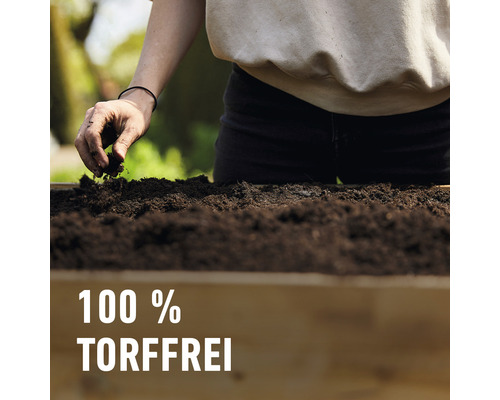 Person befüllt ein Hochbeet mit torffreier Erde.
