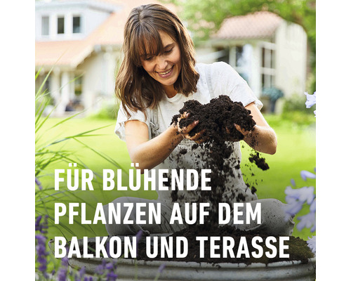 Frau füllt Pflanzerde in einen Topf auf dem Balkon oder der Terrasse.