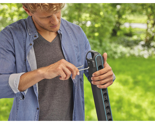 Mann montiert eine Gartendusche im Freien.