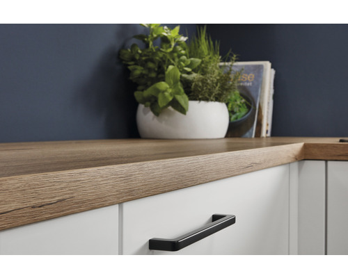 Küchenarbeitsplatte aus Holz auf weißen Schränken mit schwarzen Griffen.