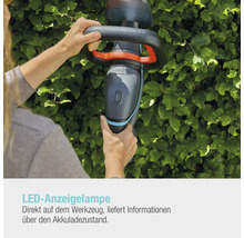 Person bedient eine Akku Heckenschere der Marke Gardena vor einer grünen Hecke.