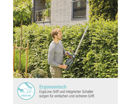 Mann schneidet Hecke mit einer Heckenschere im Garten.