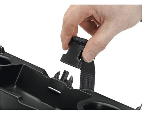 Person befestigt einen Gurt an einem schwarzen Behälter.