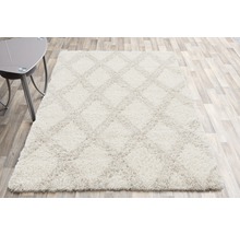 Rechteckiger, hellfarbiger Hochflor Teppich mit Rautenmuster.