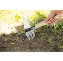 Hand hält eine Pendelhacke mit Holzstiel im Garten.
