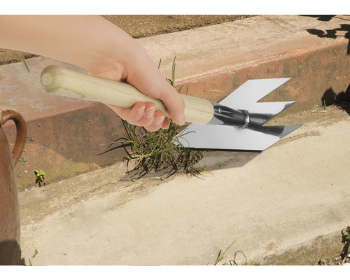 Hand hält einen Fugenkratzer mit Holzgriff zum Entfernen von Unkraut aus Fugen.