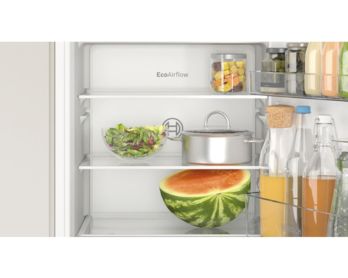 Innenansicht eines Kühlschranks mit Lebensmitteln wie Salat, Wassermelone und Getränken