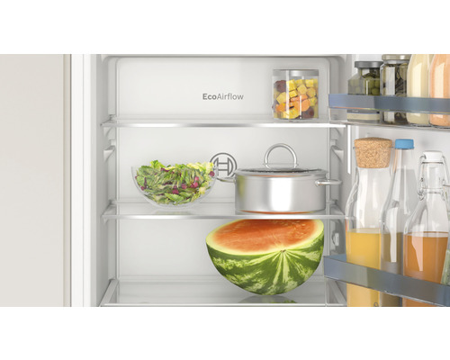 Innenraum eines Kühlschranks mit Lebensmitteln wie Wassermelone, Salat und Kochtopf