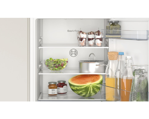 Innenraum eines Kühlschranks mit verschiedenen Lebensmitteln wie Salat, Wassermelone und Getränken