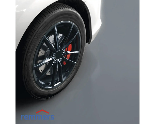 Detailaufnahme eines Autoreifens mit Felge auf einem Garagenboden.