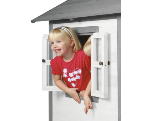 Mädchen schaut aus Fenster eines Spielhauses aus Holz