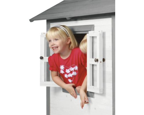 Mädchen schaut aus dem Fenster eines Holzspielhauses