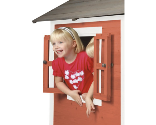 Mädchen schaut aus dem Fenster eines Spielhauses aus Holz