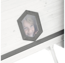 Ein Kind schaut aus einem fünfeckigen Fenster eines Holzspielhauses.
