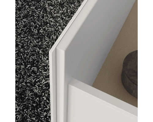 Detailansicht eines weißen Möbelstücks mit Schublade und Teppich