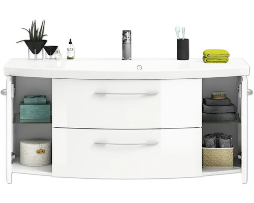 Weißer Waschtisch mit offenem Schrank, Ablageflächen und diversen Badutensilien.