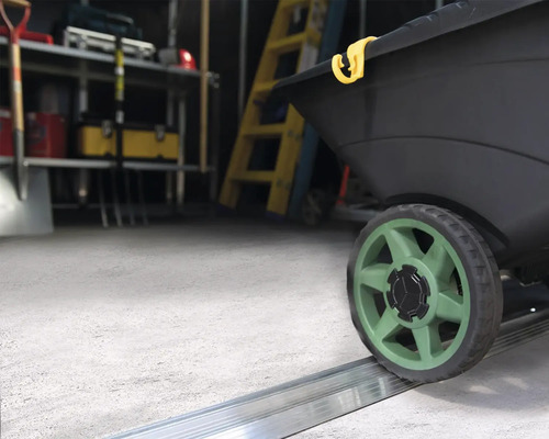 Nahaufnahme eines schwarzen Streuwagens mit grünen Rädern in einem Abstellraum