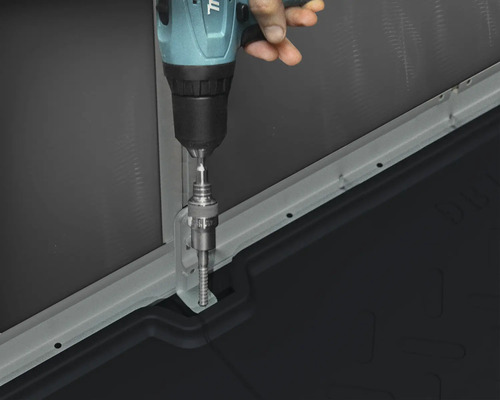 Eine Person montiert mit einem Akkubohrer eine Metallschiene an einem Bauelement.