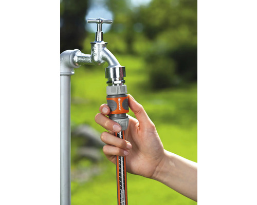 Person schliesst einen Gartenschlauch an einen Wasserhahn an