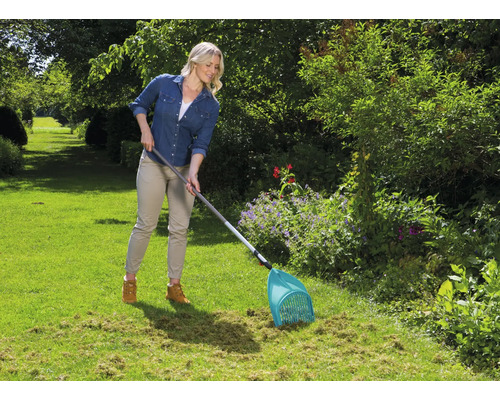 Frau benutzt einen Laubsammler im Garten.