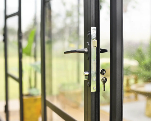 Nahaufnahme einer schwarzen Glastür mit Türgriff, Schloss und Schlüsseln.