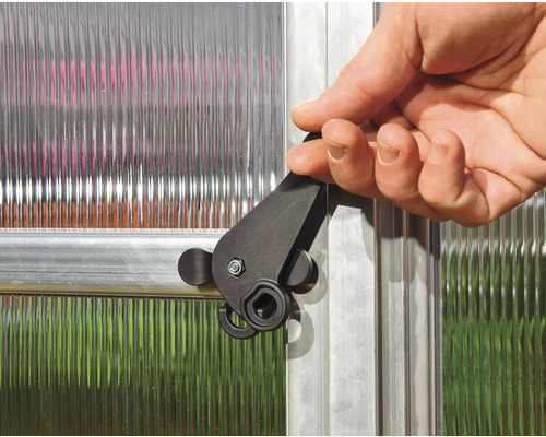 Ein Mann betätigt einen schwarzen Verschluss an einem Gewächshausfenster