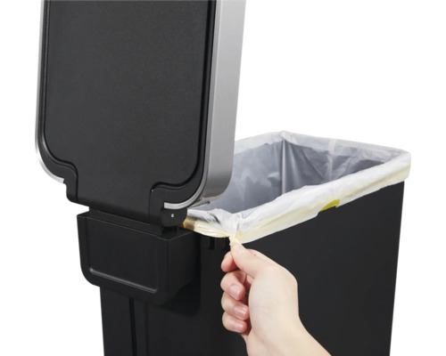 Detailaufnahme eines Abfallbehälters mit Müllbeutel und Hand