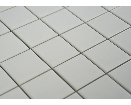 Nahaufnahme von quadratischen Fliesen, die diagonal angeordnet sind und ein wiederholendes Muster bilden.