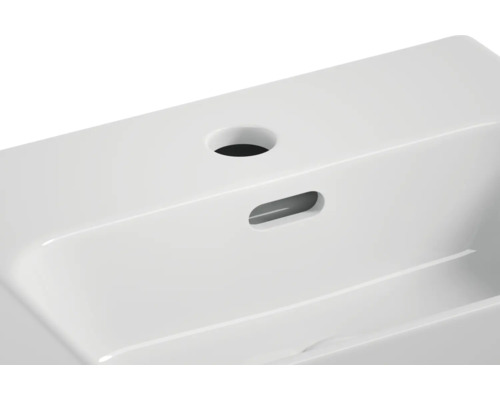 Detailansicht eines weißen Waschtischs aus Keramik mit Hahnloch und Überlauf