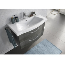 Waschtisch mit Unterschrank, Waschbecken, Armatur, Handtuch und Badaccessoires in einem Badezimmer