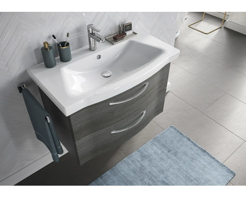 Waschtisch mit Unterschrank, Waschbecken, Armatur, Handtuch und Badaccessoires in einem Badezimmer