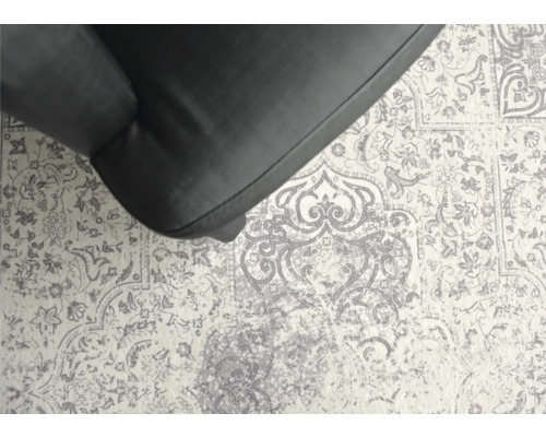 Detailansicht eines Teppichs mit floralem Muster unter einem Möbelstück