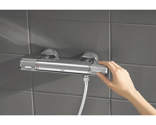 Aufputz-Thermostatarmatur im Badezimmer mit Hand am Temperaturregler