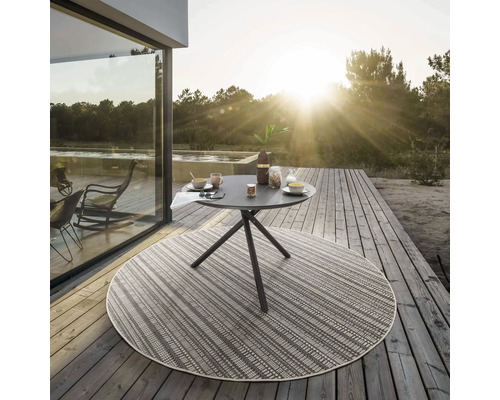 Outdoor-Szene mit rundem Tisch und Frühstücksgedecken auf einer Terrasse mit rundem Teppich