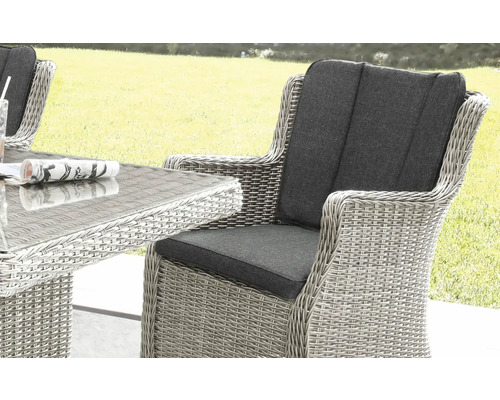 Nahaufnahme von einem geflochtenen Gartenstuhl mit Armlehne und grauen Polstern, Teil einer Sitzgruppe