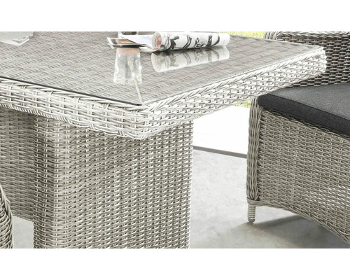 Detailansicht eines Gartentisches mit Glasplatte und Rattanoberfläche sowie eines Stuhls mit Kissen