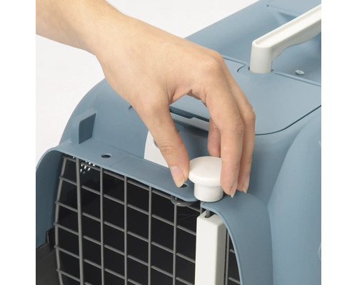 Detailaufnahme einer Hand, die einen Drehverschluss an einer blauen Tiertransportbox bedient