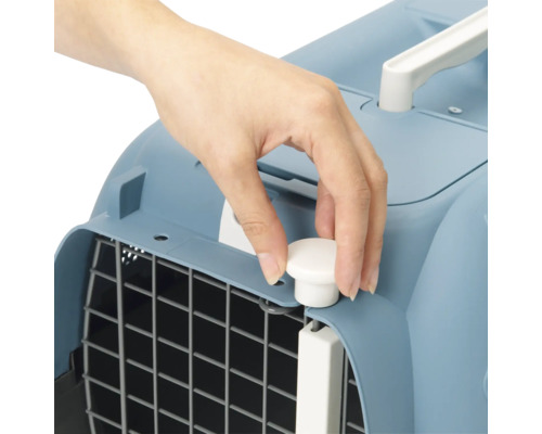 Detailansicht einer Hand, die einen Verschluss an einer Haustiertransportbox betätigt.