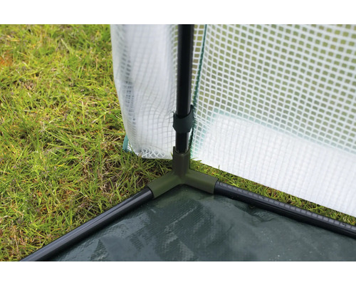 Detailaufnahme eines Gewächshauses mit Folie und grünem Gestell auf Gras
