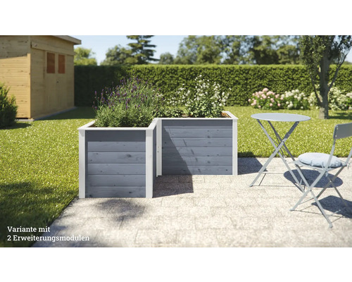 Zwei graue Holz-Hochbeete mit Pflanzen im Garten, neben einem Gartentisch mit Stuhl.